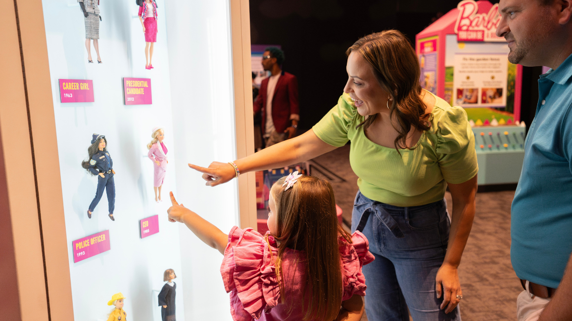 A girl and her parents play at an exhibit called Barbie at Science museum oklahoma