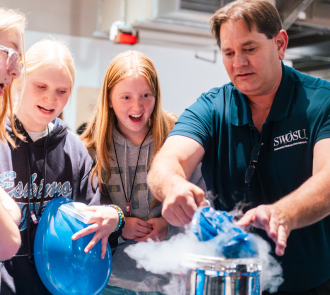 Girls are amazed at an activity a community partner is hosting at Women in steam event at science museum oklahoma