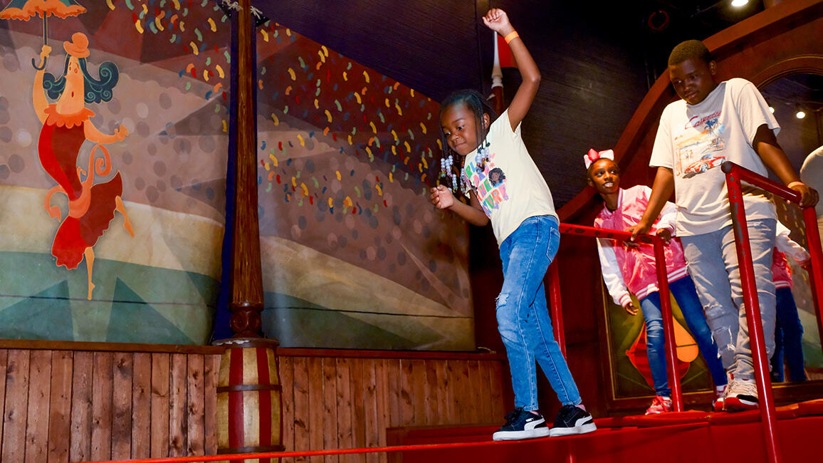 Children balance on a tightrope activity inside CurioCity at Science Museum Oklahoma, engaging in hands-on physical science exploration.