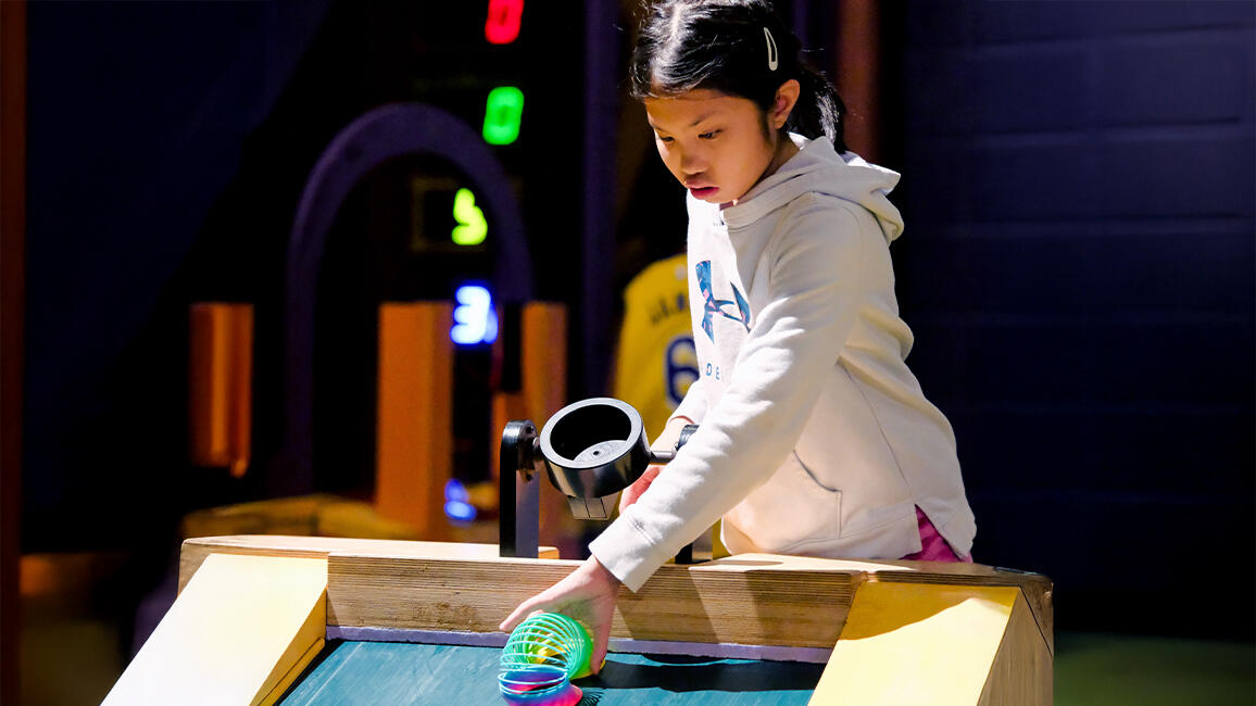 A young visitor experiments with motion and gravity using a slinky in the CurioCity exhibit at Science Museum Oklahoma.