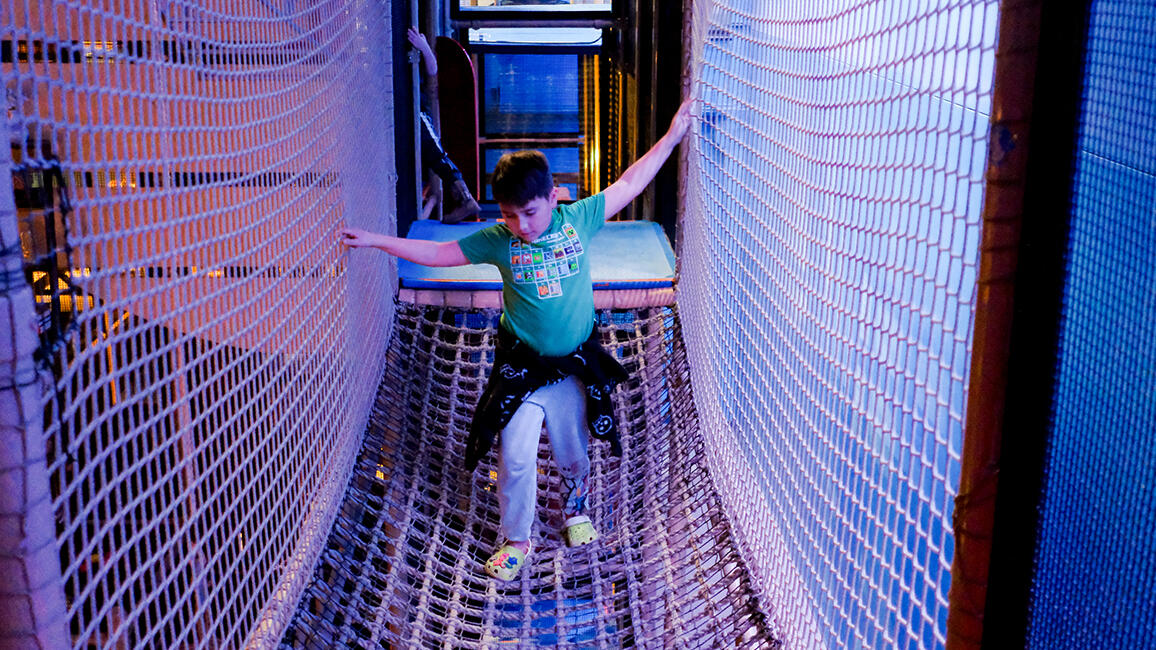 Child navigating a rope bridge in CurioCity at Science Museum Oklahoma, part of a hands-on interactive STEM exhibit.