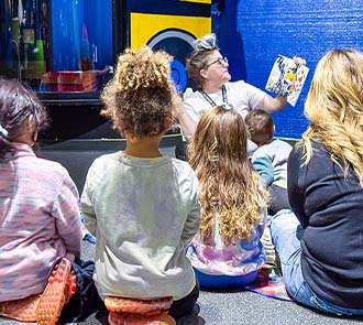 Small children listen in a group listen to storytime at science museum oklahoma.