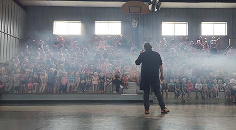 Science Museum Oklahoma staff member educator speaks to an auditorium of students at a rural school.
