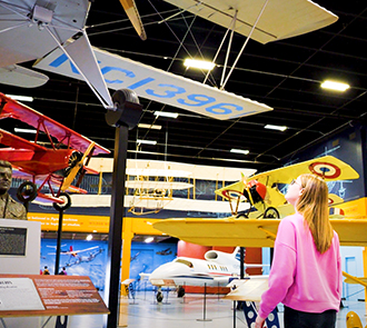 A girl looks up at vintage airplanes suspended from the ceiling inside the Oklahoma Aviation Gallery at Science Museum Oklahoma.