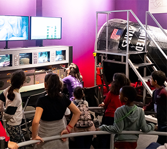 Children gather inside the Destination Space exhibit at Science Museum Oklahoma to explore space science and astronaut training simulations.
