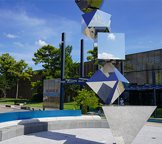 A large geometric sculpture reflects the sky outside Science Museum Oklahoma, welcoming visitors to a world of science, art, and discovery.