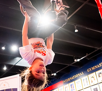 A child hangs upside down on rings inside the International Gymnastics Hall of Fame at Science Museum Oklahoma.