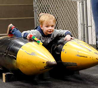 A toddler plays on a submarine prop in the Navy Gallery at Science Museum Oklahoma, part of the museum’s hands-on military science exhibits.
