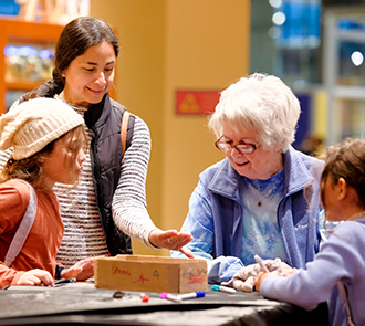Multi-generational visitors collaborate on a hands-on building project in the Tinkering Garage at Science Museum Oklahoma.