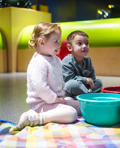 Two children listen to a storytime science program educator.