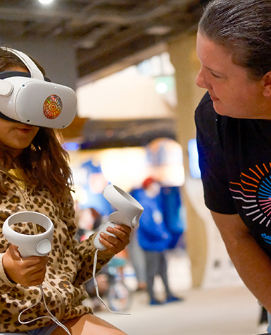 A volunteer helps a child with avirtual reality headset at Science Museum Oklahoma