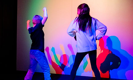Two children interact with colorful lights and shadows in a hands-on science exhibit at Science Museum Oklahoma.