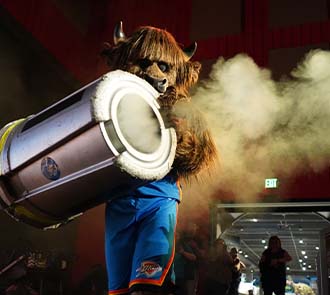 The Oklahoma City Thunder mascot Rumble uses a fog cannon during a science show at Science Museum Oklahoma, surrounded by excited guests.
