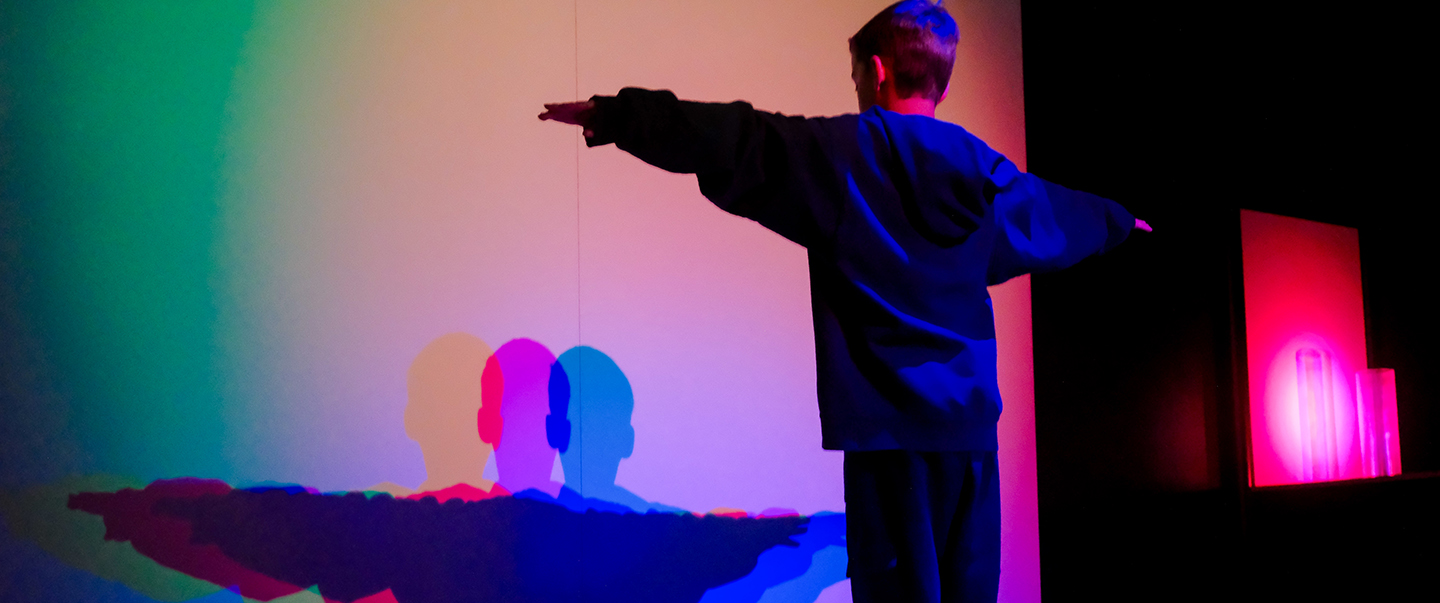 Boy spreads his arms to reveal colors in an exhibit at Science Museum Oklahoma.