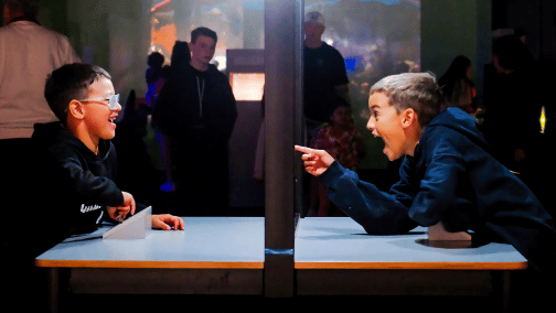 Two boys point and laugh having fun at science museum oklahoma because of their memberships.