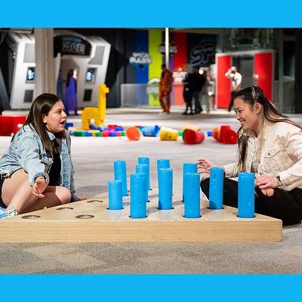 Two women are laughing while playing a giant pin game at a SMO 21 at Science Museum Oklahoma.