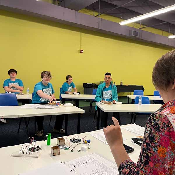 An educator is informing several teen apprentices that they have been accepted into a prestigous program through NASA.