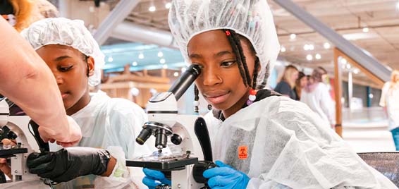 A child looks into a microscope at Science Museum Oklahoma's Women in STEAM conference in OKC.