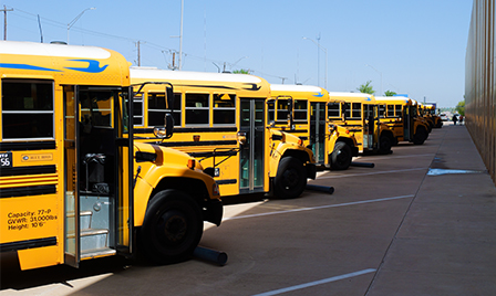 A row of yellow school buses parked outside Science Museum Oklahoma for a day of STEM education and field trip fun.