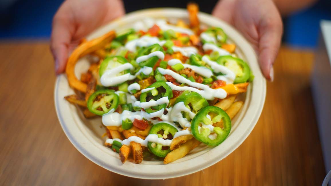 A bowl of loaded fries topped with jalapeños, green onions, and sour cream from Pavlov’s Café inside Science Museum Oklahoma.