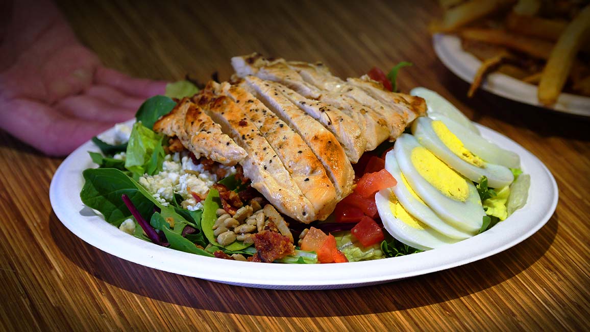 A fresh Cobb salad from Pavlov’s Café at Science Museum Oklahoma, topped with grilled chicken, sliced boiled eggs, tomatoes, feta cheese, bacon bits, sunflower seeds, and mixed greens.