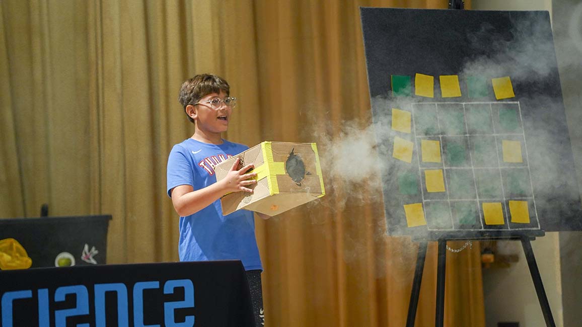 Student participates in a Science Museum Oklahoma STEAM Live school presentation using a vortex box to explore hands-on science concepts.