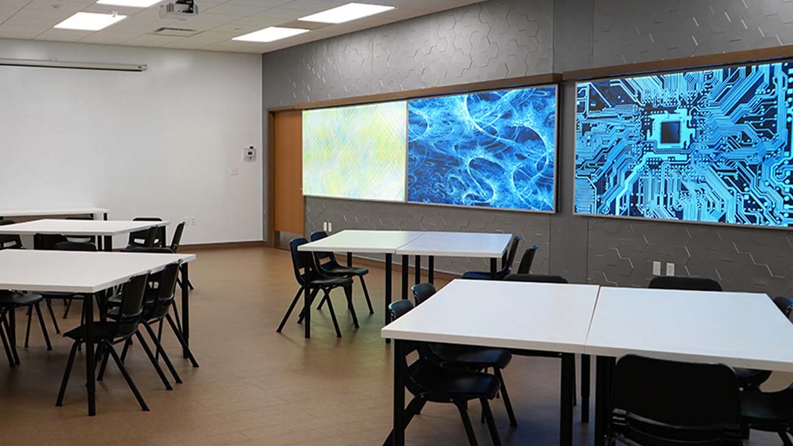 Modern lab-themed party room at Science Museum Oklahoma with sleek white tables, digital wall art, and flexible space ideal for curious young scientists