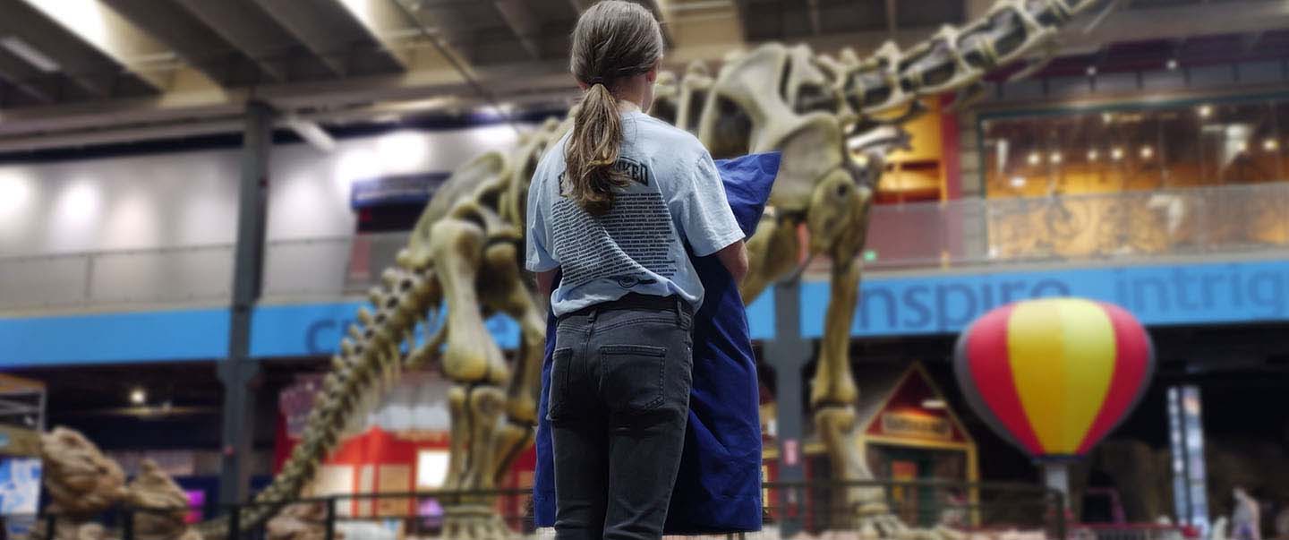 A child holding a pillow is trying to decide where she will sleepover at a science museum overnight in OKC.