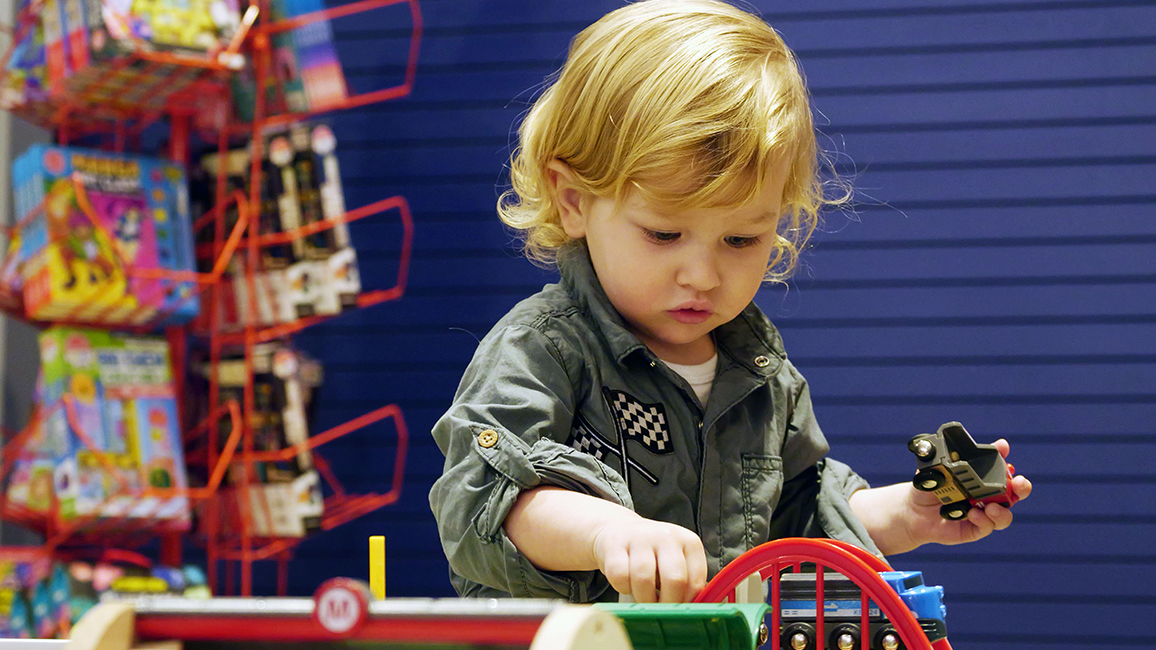 A young child explores a BRIO train set at the Science Shop inside Science Museum Oklahoma, where hands-on STEM toys spark curiosity.