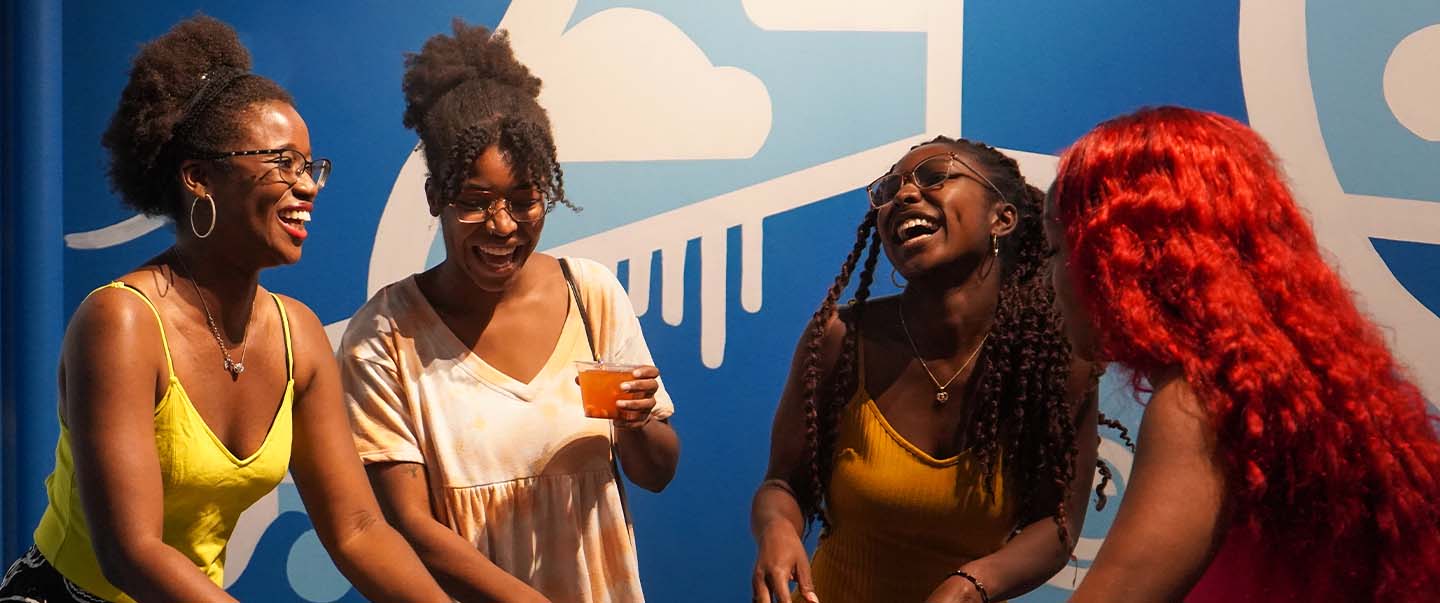 A group of adults enjoy a hands-on science exhibit with drinks and laughter during SMO21+ at Science Museum Oklahoma, an after-hours event for ages 21 and up.