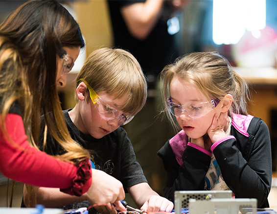 Three children lean in to make something together at Science Museum Oklahoma.