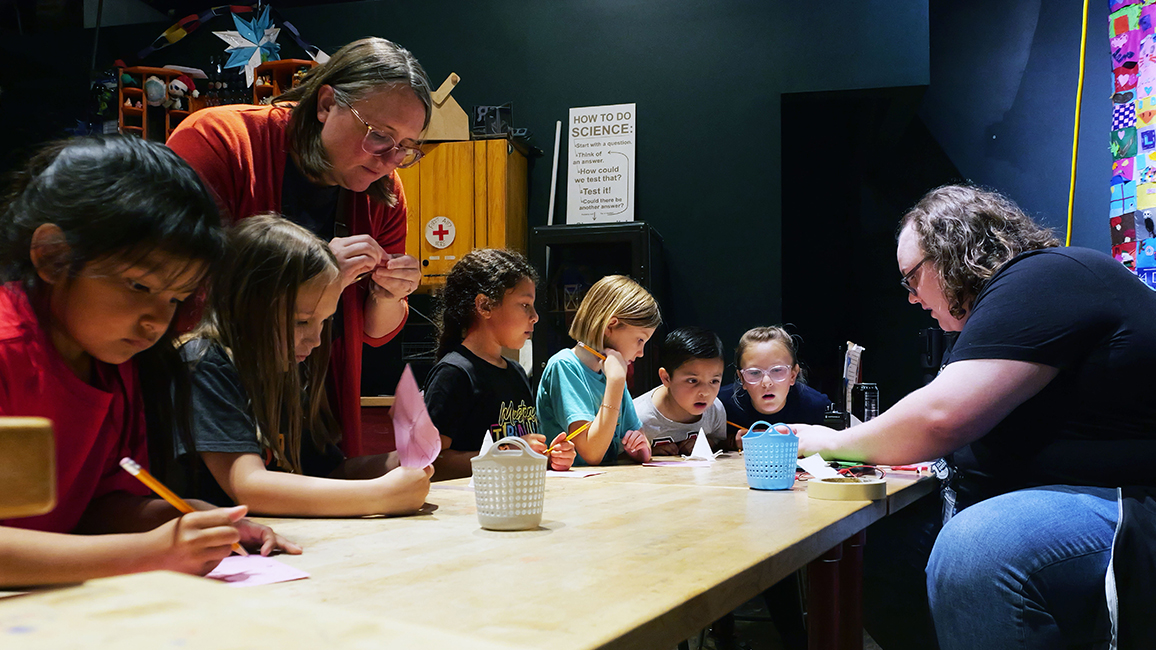 A family works with a staff member at Science Museum Oklahoma to work on a craft project in Tinker Works.