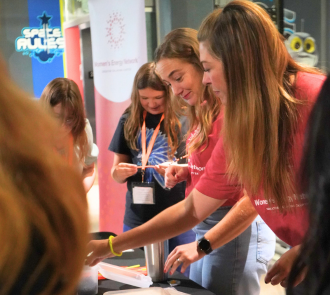 woman smiles helping students at a table at the women in steam conference