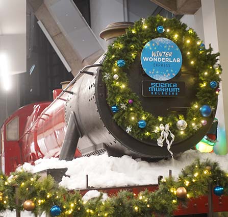Winter Wonderlab Express train decorated with lights and garland at Science Museum Oklahoma's holiday event. 