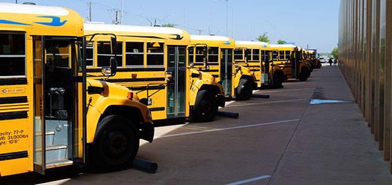 A row of yellow school buses lines the parking lot outside Science Museum Oklahoma, ready to drop off students for a field trip visit.