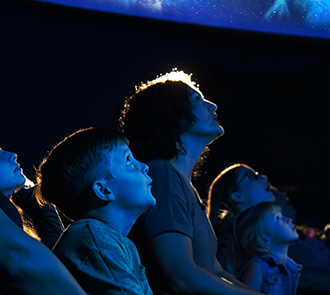 Mother and children on the edge of their seats in wonder at the Love’s Planetarium at Science Museum Oklahoma.