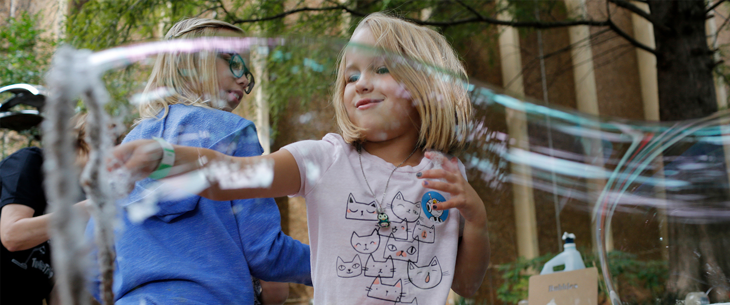 Girl playing with a giant bubble wand