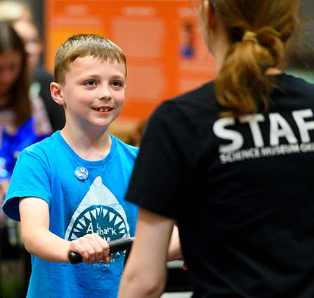 Science Museum Oklahoma staff member engages with a child during a hands-on science exhibit. 